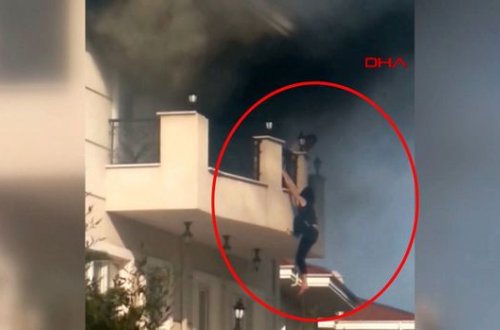 Yanğından xilas olmağa çalışan qadın bir neçə dəqiqə eyvandan sallanmış vəziyyətdə qaldı - VİDEO